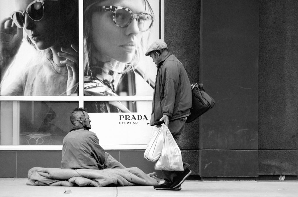 Homeless sitting outside of Prada advertisement